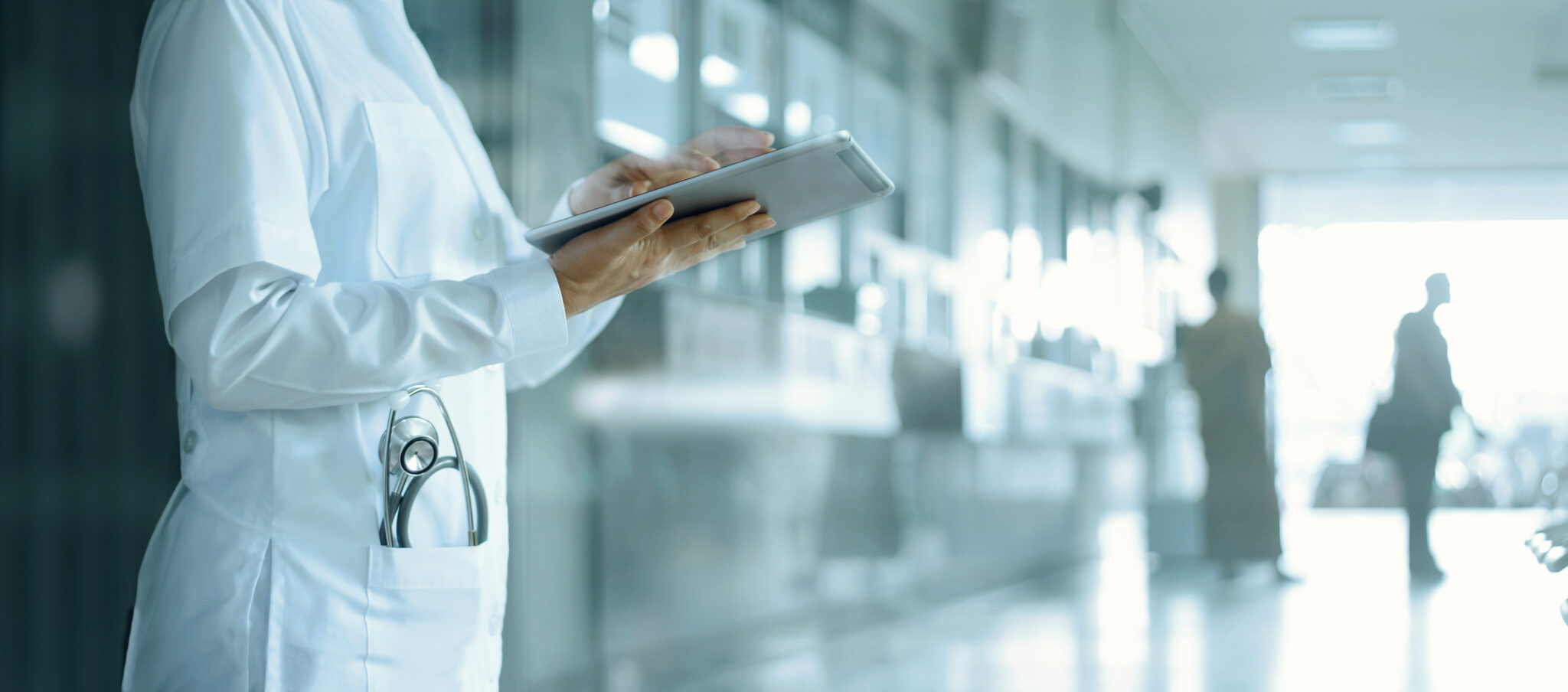 Doctor reading notes in a hosital hallway.